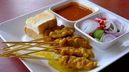 Grilled pork or satay pork served with peanut sauce, cucumber salad sweet  and grilled toast, Asian appetizer. 