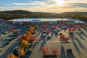 Aerial view grocery shopping mall and many colorful cars parked on parking lot with lines and markings for parking places and directions. Place for vehicles in front of a strip mall plaza
