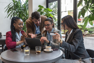 Group of young business people enthusiasts experts try out their new internet application in a cafeteria for online booking shopping ordering. Owners of a small company meeting in a restaurant