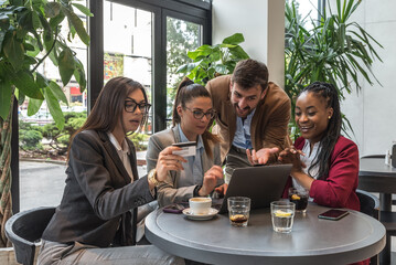 Group of young business people enthusiasts experts try out their new internet application in a cafeteria for online booking shopping ordering. Owners of a small company meeting in a restaurant