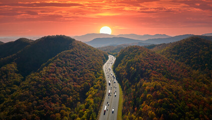 Aerial view of I-40 freeway in North Carolina leading to Asheville through Appalachian mountains in golden fall with fast moving trucks and cars. Interstate transportation concept