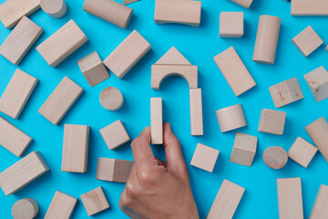 man forming a house with wooden building blocks
