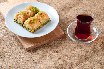 Traditional pistachio baklava with Turkish tea.A plate baklava on burlap sack.Traditional Ramadan dessert
