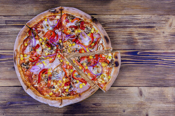Mexicana pizza with salami sausage, vegetables and parmesan cheese on a wooden table. Top view