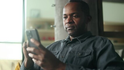 Portrait of handsome mature african american man browse products in internet online shopping store planning trip travel or swiping through profiles on dating app on smartphone at home Choice concept