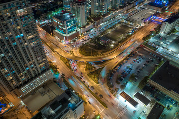 View from above of brightly illuminated city street with dense traffic and high skyscraper buildings in downtown of Sunny Isles Beach in Florida, USA. American tourist urban district at night