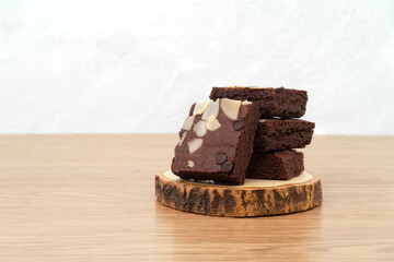 Brownies on wooden tray on wooden background. Chocolate brownie with sliced almond nuts toppings. Chocolate Brownie pieces. selective focus.