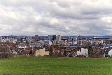 Fototapeta premium Scenic view over rural landscape and agriculture fields with skyline of City of Wallisellen in the background on a cloudy winter day. Photo taken February 26th, 2023, Zurich, Switzerland.
