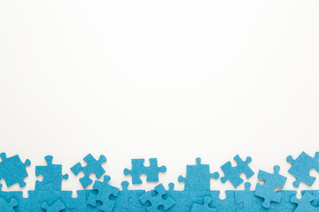 Unfinished blue puzzle pieces on white table background. Closeup. Empty place for text. Top down...
