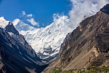 Contrasting mountains with blue sky. Foreground of barren mountain with the background of snow covered mountains with copy space.