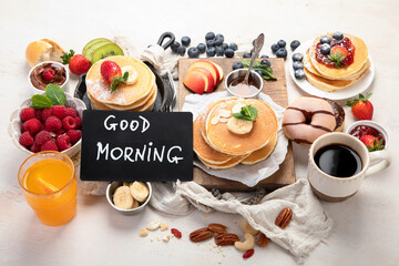 Pancakes with fresh fruits, donuts and coffee on a white background.