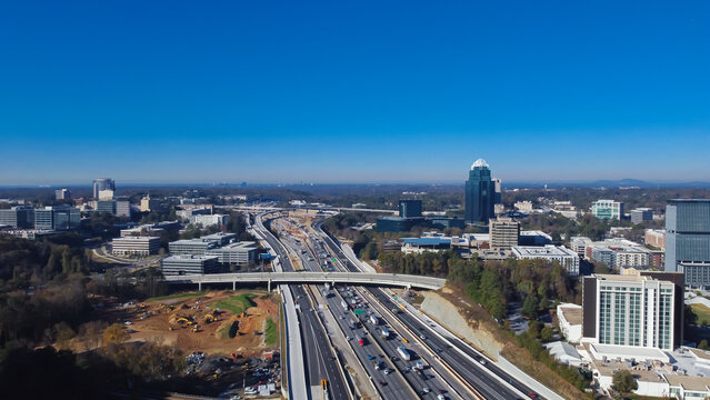 Construction site with heavy machines working along busy Interstate 285 highway, Perimeter Center office towers skylines, midtown Atlanta, Georgia, USA