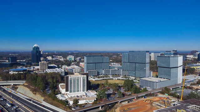 Construction site with heavy machines working along busy Interstate 285 highway, Perimeter Center office towers skylines, midtown Atlanta, Georgia, USA