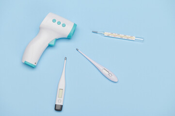 Flat lay. A set of modern infrared electronic thermometer with digital display and glass mercury thermometer, for measuring body temperature, isolated blue background. Healthcare and medicine concept