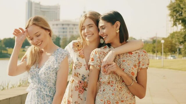 Three young beautiful smiling hipster girls in trendy summer sundress.Sexy carefree women posing on the street background. Positive models having fun and hugging. Walking after shopping at sunset
