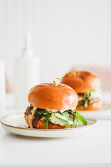 Two delicious homemade burgers with beef, cheese and vegetables on white wooden table
