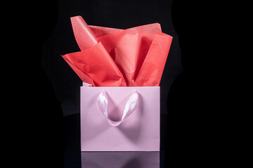 Craft paper gift bag with tissue paper isolated on a black background