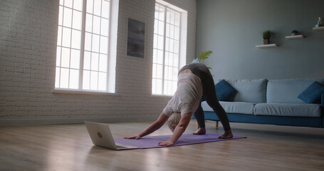 Caucasian woman practice yoga Downward Facing dog to meditation enjoy and relax with yoga. Mature woman practicing yoga at home. Senior female athlete keeping a healthy lifestyle - wellness concept