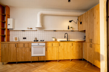 Photo of modern kitchen interior made in wooden materials with white walls on sunshine