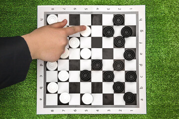 close-up of a girl's hand playing black and white checkers