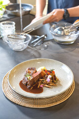 Medium Rare grilled Beef Steak with fried sliced mushroom in front of blur sink and washing glass bowl behind.
