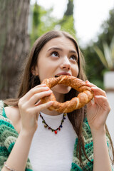 Brunette woman eating traditional turkish simit bread in Istanbul.