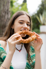 Portrait of young woman eating simit bread and looking at camera in Istanbul.