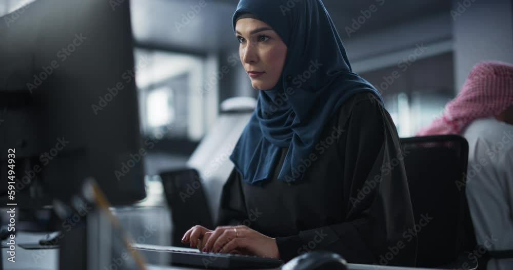 Poster Thoughtful Middle Eastern Engineer Working on Computer in a Technological Corporate Office. Young Muslim Woman Writing Software Code for an Innovative Internet and Software as a Service Project