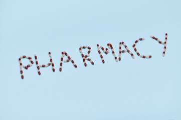 The word PHARMACY laid out with medical capsule on blue background with copy advertising space. The concept of World Pharmacist Day. Pharmaceutical business and industry. World Health Day. Top view