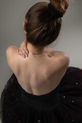 back of a seated female ballet dancer wearing a black tutu dress with her hair up, active lifestyle, wallpaper