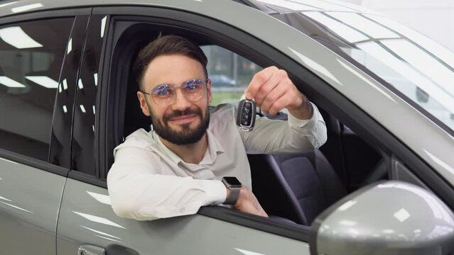 Business Man smiling and showing car keys in a car dealership. Right hand drive car