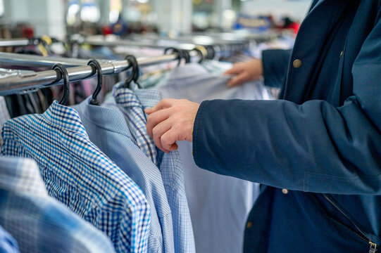 Man choosing clothes from rack in store