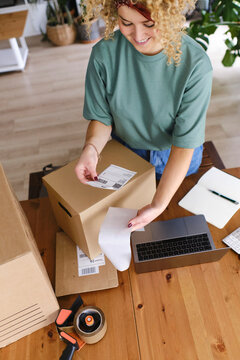 Smiling young woman with shipping label at desk