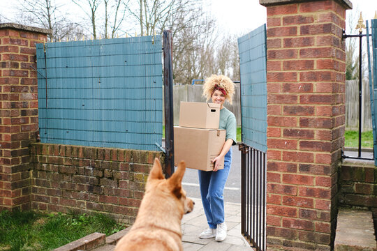Happy young woman delivering packages entering through gate