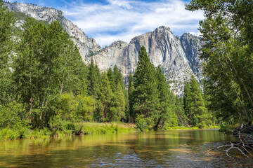 View of the Yosemite falls from the middle of the tranquil Merced River below Swinging Bridge in summer, Yosemite National Park.