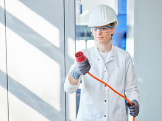 Woman wearing lab coat examining power plug in laboratory