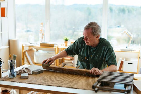 Senior man scarping wood in workshop