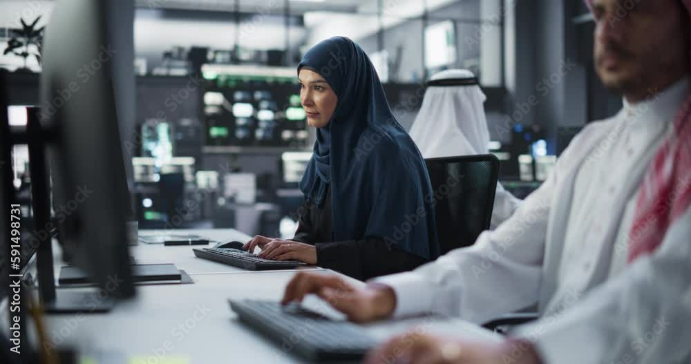 Poster Diverse Young Arab Colleagues Working on Computers in a Research Laboratory. Focus on Middle Eastern Female Software Developer Working on a Solution for Their Collaborative Industrial Tech Project