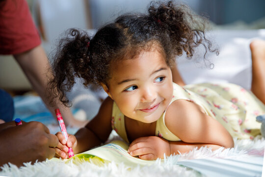 Thoughtful smiling girl lying on carpet at home