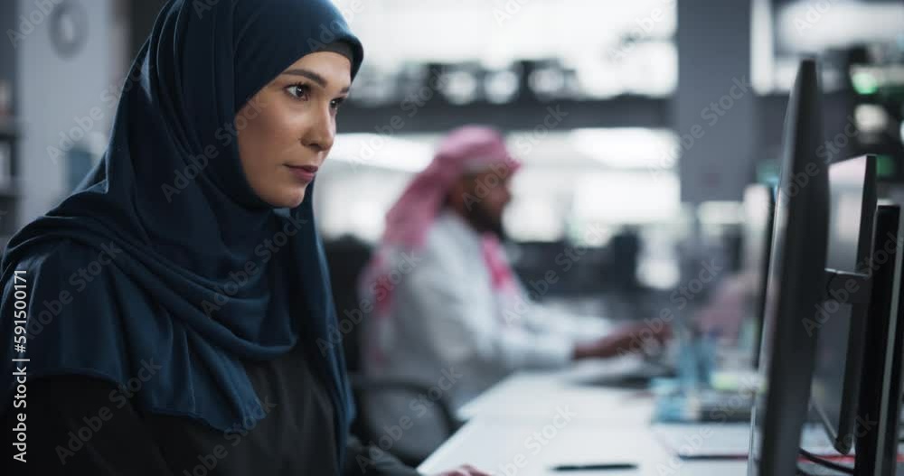 Poster Portrait of a Middle Eastern Software Developer Working on Computer in a Technological Corporate Office. Young Muslim Woman Writing Code for an Innovative Internet and Software as a Service Project