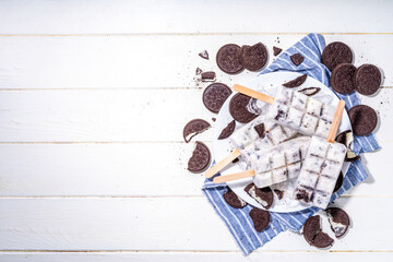 Cream and cookie popsicles ice cream, vanilla ice-cream lollipops with chocolate crushed cookies crumbles, with a lot of cookies on kitchen table background