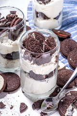 Cream and cookie layered dessert. Homemade oreo trifle, vanilla chocolate cookie layered cheese cake in glass, variation of traditional american breakfast dessert
