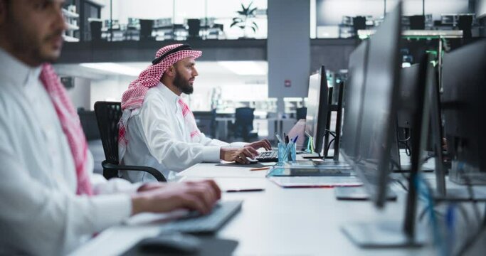 Portrait of a Middle Eastern Engineer Working on Desktop Computer in a Technological Office Environment. Arab Software Developer Researching New Ideas to Problem Solve a Technical Assignment