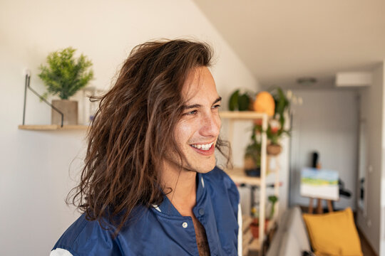 Happy young man with long hair at home