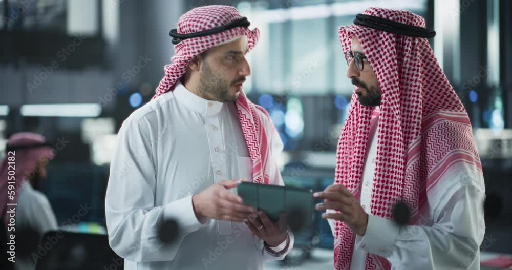Fototapete Two Young Muslim Software Engineers Use Tablet Computer to Discuss a Technological Project in a Modern Industrial Office. Arab Scientists Work in Research and Development Center