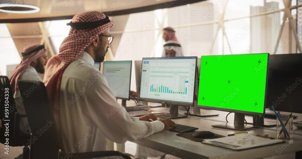 Poster arab chief financial officer working on desktop computer with green screen mock up display. young mi