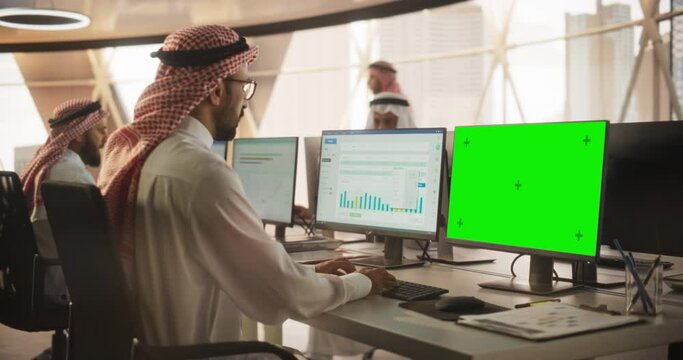 Arab Chief Financial Officer Working on Desktop Computer with Green Screen Mock Up Display. Young Middle Eastern Specialist Analyzing Corporate Banking Account, Researching Investment Opportunities
