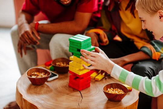 Happy friends playing block removal game on table at home