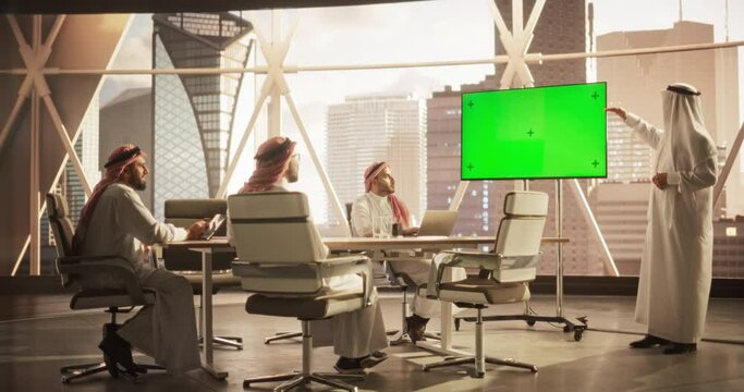 Arab Businessman Shows Data to a Group of Saudi Investors. TV Screen with Green Screen Mock Up Display. Business Meeting Presentation in Conference Room in Modern Office