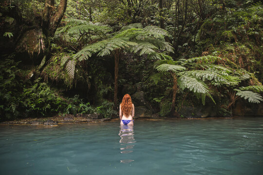 Young redhead woman in bikini standing in lake